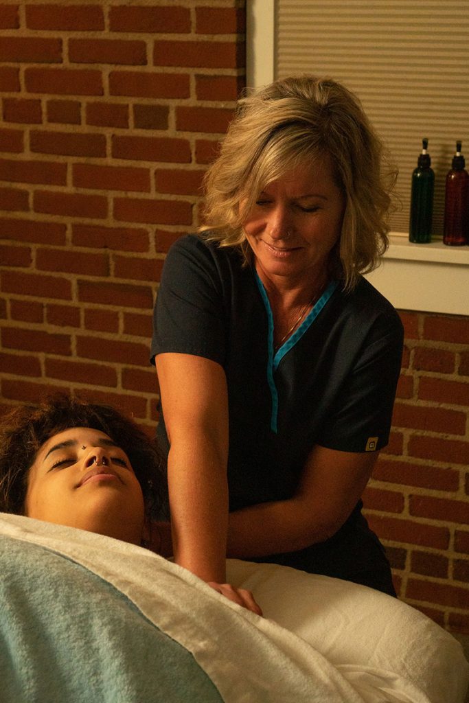 woman massaging a patient on table with blanket